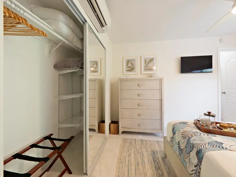Primary bedroom closet with luggage rack and dresser